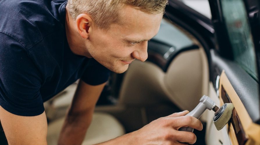 Man at car service polishing car details